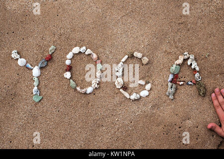 Schreiben mit Muscheln text Yoga am Sandstrand Stockfoto
