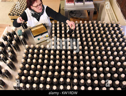 Gernrode, Deutschland. 27 Dez, 2017. Mitarbeiter Carola Bergmann labels Kräuterlikör im Harz Likör Manufaktur in Gernrode, Deutschland, 27. Dezember 2017. Vor zwei Jahren die studierte Steuerfachmann Nicole Tandera übernahm die mehr als 60-jährige Traditionsunternehmen und trug es auf erfolgreich. 20 verschiedene Kräuter- und Fruchtsaft Liköre und andere destillate sind in ihrer Manufaktur hergestellt. Credit: Waltraud Grubitzsch/dpa-Zentralbild/ZB/dpa/Alamy leben Nachrichten Stockfoto