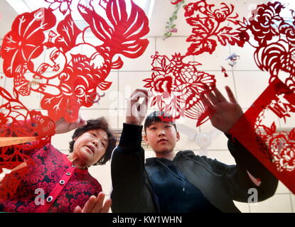 (171229) - TANGSHAN, Dez. 29, 2017 (Xinhua) - Jia Shurong (L), ein Papier schneiden artisan, unterrichtet ein Mädchen an Hengqu experimentelle Middle School in Luanxian County, im Norden der chinesischen Provinz Hebei, Dez. 29, 2017. Die Regierung hat sich dazu ermutigt Schulen Papier schneiden Klasse der Jugend die traditionellen Kulturen zu unterrichten, zu öffnen. (Xinhua / Mu Yu) (wjq) Stockfoto