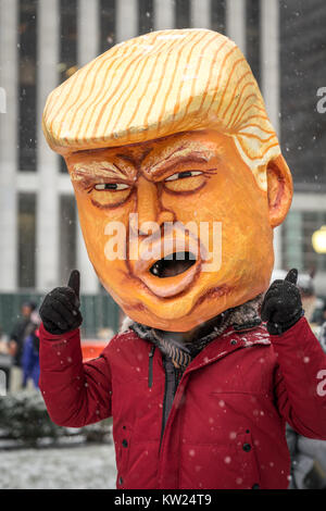 New York, USA, 30. Dez. 2017. Ein Mann mit einer Maske spöttisch eine verkettete US-Präsident Donald Trump gibt die Daumen oben nach einem Protest in Midtown New York City. Demonstranten braved einen Schneesturm Amtsenthebungsverfahren ist Trumpf zu verlangen. Foto von Enrique Ufer/Alamy leben Nachrichten Stockfoto