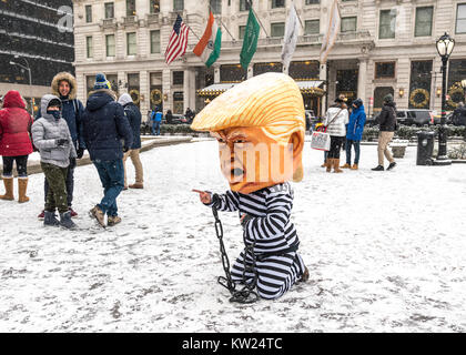 New York, USA, 30. Dez. 2017. Eine Demonstrantin mit einer Maske spöttisch eine verkettete US-Präsident Donald Trump auf einem Gefängnis uniform führt vor Touristen neben New York City Plaza Hotel. Demonstranten braved einen Schneesturm Amtsenthebungsverfahren ist Trumpf zu verlangen. Foto von Enrique Ufer/Alamy leben Nachrichten Stockfoto