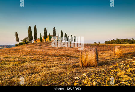 Wunderschöne Toskana Landschaft mit traditionellen Bauernhof Haus und Heuballen im goldenen Abendlicht, Val d ' Orcia, Italien Stockfoto