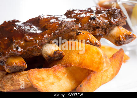 Leckere Rippchen mit Soße und Gurken auf eine weisse Platte Stockfoto