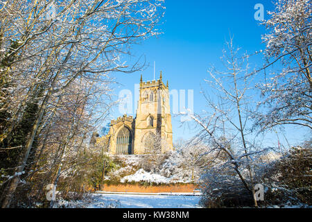 Landschaft schoss der St. Mary's Kirche, Kidderminster, Worcestershire, von Bäumen eingerahmt, auf einem sonnigen Morgen mit Schnee auf dem Boden. Stockfoto