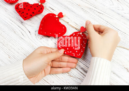 Valentine Hintergrund mit genähten Kissen diy Handarbeit Herzen in der Frau die Hände am rustikalen, mit Holz Planken. Glückliche Liebhaber Tag, kopieren. Stockfoto