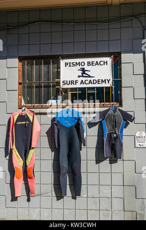 Tauchanzüge aufhängen von einem vergitterten Fenster auf der Seite von einem Betonklotz Gebäude in Pismo Beach, Kalifornien zu trocknen. Stockfoto