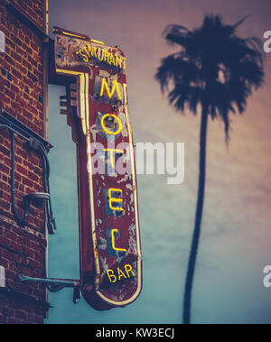 Grunge Motel Restaurant Bar Leuchtreklame gegen eine Palme im Sonnenuntergang Stockfoto