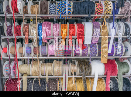 Isolierte Schuß von Pailletten Bänder, bunte Seil und anderen Bric-a-brac, auf einem Display Rack Stockfoto