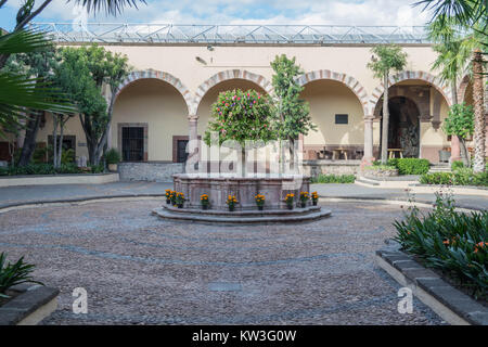 Das Zentrum Brunnen im Innenhof, mit architektonischen Torbögen und verschiedenen Bäumen, am Instituto Allende, in San Miguel de Allende, Mexiko Stockfoto