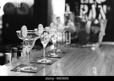 Dieses Schwarzweiß-Foto zeigt eine Auswahl an alkoholischen Getränken, die an einer Bar serviert werden, und bietet einen Einblick in die Barkultur aus der Mitte des 20. Jahrhunderts. Stockfoto
