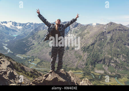 Eine touristische hob seine Hände zum Himmel zeigen die Freude an der Eroberung der Gipfel. Menschen aktiv in Form von ständigen am Rande einer Klippe ein Stockfoto