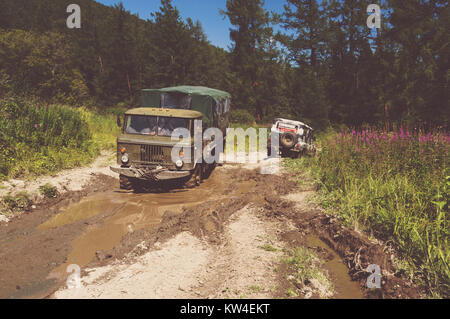 Schwere leistungsstarke Lkw-Gelände Fahrzeuge cle mit Off-road-Räder. Große off-road Fahrzeug zieht Pross kleine SUV. Das Auto im Schlamm stecken. Stockfoto