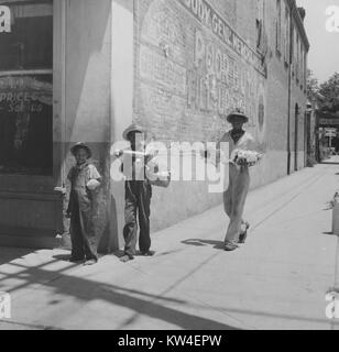 Jungen stehen auf einem Bürgersteig durch ein kommerzielles Gebäude verschiedene Güter, in Port Gibson, Mississippi, August, 1940. Stockfoto