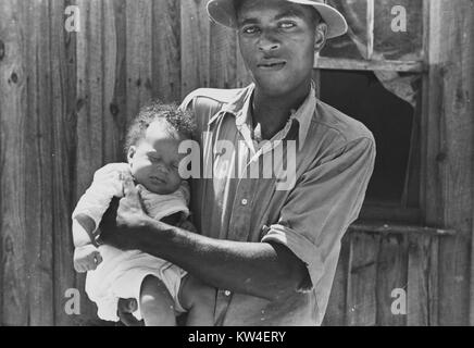 Ein Pächter tragen ein Button-up Shirt und Hut hält seine jungen Kind, in Lee County, Mississippi, August, 1935. Von der New York Public Library. Stockfoto