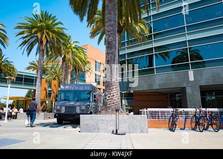 Im Googleplex, dem Sitz der Firma Google Search Engine im Silicon Valley Stadt Mountain View, Kalifornien, einem Lkw und mehrere Fahrräder sind unter Palmen geparkt, mit Gebäuden auf dem Google Campus im Hintergrund sichtbar, Mountain View, Kalifornien, 24. August 2016. Stockfoto