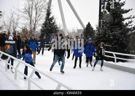 Besucher genießen Eislaufen im Schnee am Skaten Band, einen gewundenen Pfad entlang des Seeufers in Chicago's Maggie Daley Park. Stockfoto