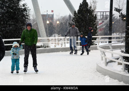 Eltern genießen Eislaufen mit ihren Kindern im Schnee am Skaten Band, einen gewundenen Pfad entlang des Seeufers in Chicago's Maggie Daley Park. Stockfoto