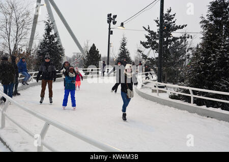 Besucher genießen Eislaufen im Schnee am Skaten Band, einen gewundenen Pfad entlang des Seeufers in Chicago's Maggie Daley Park. Stockfoto