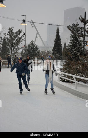 Ein paar genießt Eislaufen im Schnee am Skaten Band, einen gewundenen Pfad entlang des Seeufers in Chicago's Maggie Daley Park. Stockfoto