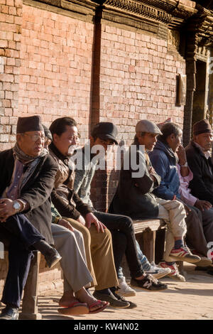 Sit-Gruppe der Nepalesischen Männer, die in der Sonne an Patan Durbar Square, Kathmandu Stockfoto