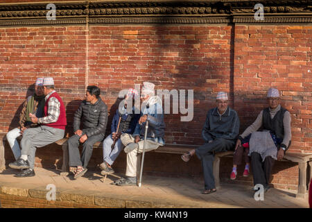 Sit-Gruppe der Nepalesischen Männer, die in der Sonne an Patan Durbar Square, Kathmandu Stockfoto