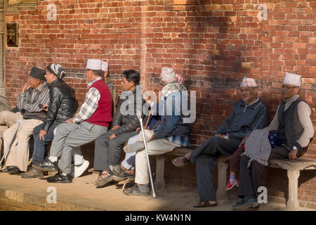 Sit-Gruppe der Nepalesischen Männer, die in der Sonne an Patan Durbar Square, Kathmandu Stockfoto