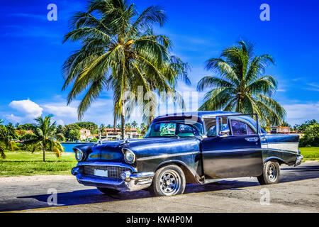 Amerikanische schwarz Chevrolet unter Palmen in Varadero Kuba - Serie Kuba Reportage geparkt Stockfoto