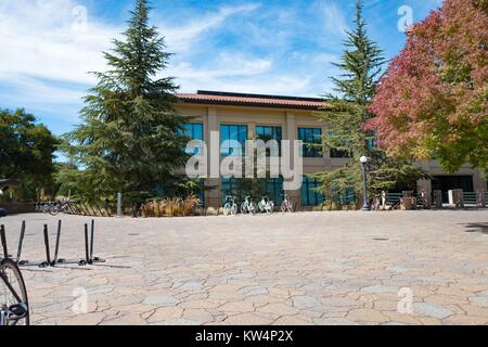 Fahrräder sind in den Stein geparkt gepflasterten Plaza außerhalb eines 2-stöckigen Gebäude, Stanford University, Stanford, Kalifornien, 3. September 2016. Stockfoto