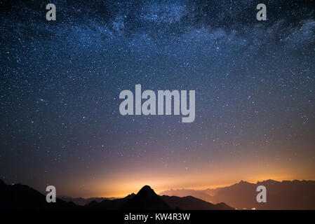 Die wunderbare Sternenhimmel auf Weihnachten und die majestätischen Gipfel der Alpen, mit glühenden Dörfer unten. Stockfoto