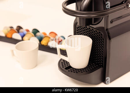 Espressomaschine, schwarz mit Kapseln dahinter. Nahaufnahme, Detail, blur Kulisse. Stockfoto