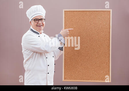 Portrait von Chefkoch in Uniform zeigen, was ist" im Menü Stockfoto