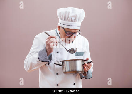 Portrait von Chefkoch in der Uniform der Verkostung der Mahlzeit Stockfoto