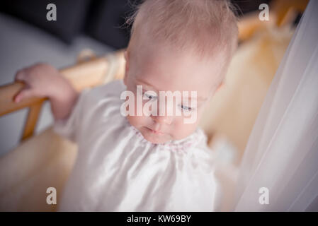 Charmante Baby ist standsing in Krippe und nach unten schauen. Stockfoto