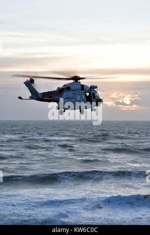 Eine Küstenwache Suche und Rettung Hubschrauber der Durchführung einer Übung über dem Meer und Wellen im rauen Wetter weg St Catherine's pointisle Wight. Stockfoto