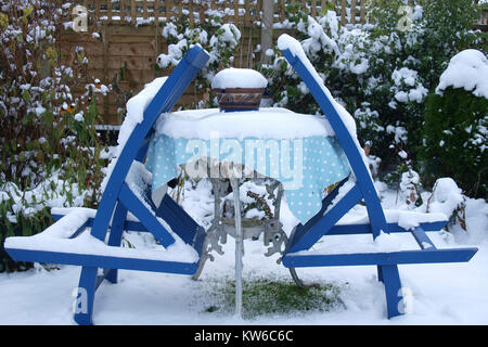 Zwei blaue Stühle gegen einen Tisch im Freien im Schnee schiefen Stockfoto