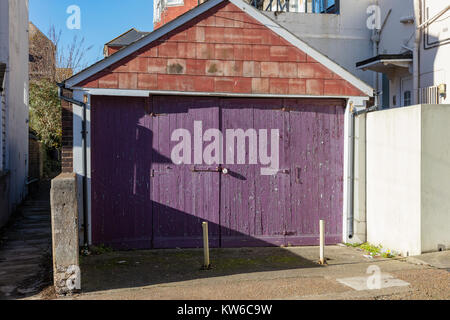 Holz Garagentor mit Peeling violette Farbe in Bexhill-on-Sea, East Sussex, Großbritannien Stockfoto