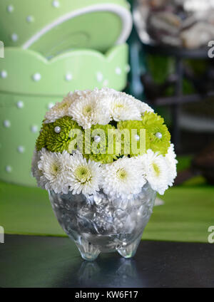 Winzige Blumenschmuck der grüne und weiße Taste, Mamas, verziert mit Perlen in einer Kristallvase. Stockfoto