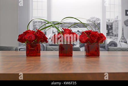 Drei Vasen mit roten Rosen und Gräser gegen einen schwarzen und weißen Hintergrund verbunden. Moderne Wohnkultur. Einzigartige Blumenarrangements. Stockfoto