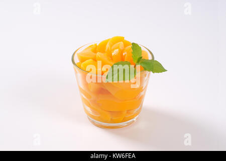 Glas von geschälten und in Scheiben geschnittenen Pfirsiche auf weißem Hintergrund Stockfoto