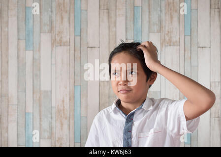 Asian Boy seinen Kopf kratzen. Junge verwirrt Ausdruck Stockfoto