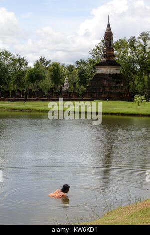 Frau in den See und die Ruinen in Sukhotai, Thailand Stockfoto