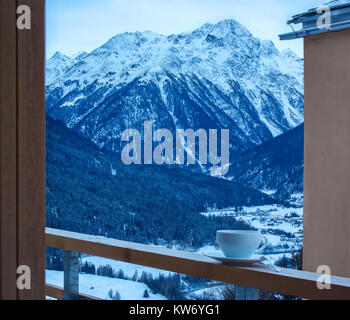 Tasse Tee auf das Geländer des Balkons bei Dämmerung. Im Hintergrund Engadin. Guarda, Unterengadin, Graubünden, Schweiz. Stockfoto