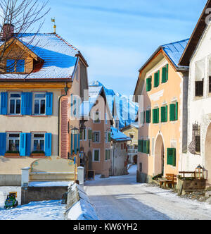 Schmale Straße mit typischen Häusern im älteren Teil von Guarda am sonnigen Morgen, Inn Bezirk, Kanton Graubünden, Schweiz. Stockfoto