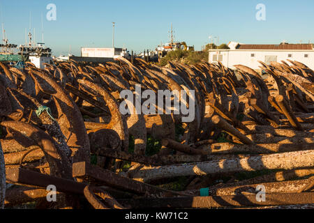 Rostiger Anker, für den Thunfischfang eingesetzt, außerhalb der Saison auf trockenem Land gestapelt im Hafen von Barbate, Costa de la Luz, Andalusien, Spanien. Stockfoto