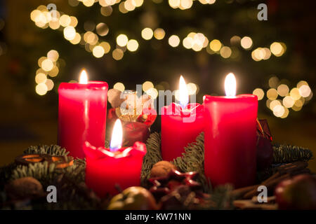 Adventskranz mit vier Kerzen, mit verschwommenen Hintergrund von Weihnachten Lichterketten beleuchtet Stockfoto