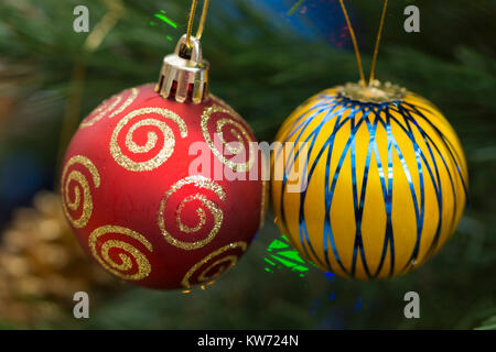 Eine Nahaufnahme eines Paares rote und gelbe Kugeln / Dekorationen hängen von einem Weihnachtsbaum Stockfoto