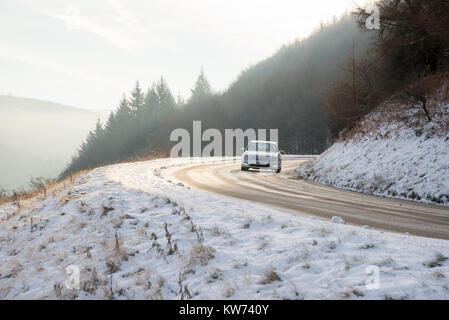 Silver Auto auf einer vereisten Straße im Winter. Country Road neben Ladybower Reservoir in der Derwent Valley, Derbyshire, England. Stockfoto