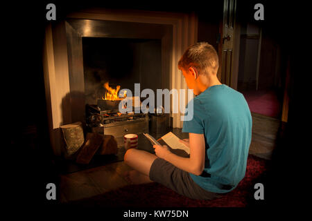 Teenager lesen Neben dem Feuer. Hygge Stockfoto