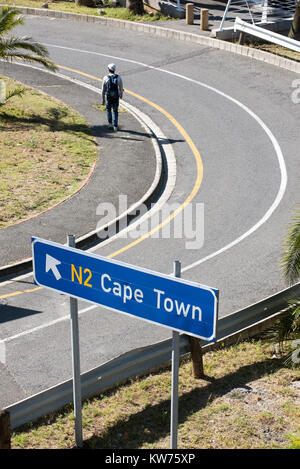 Junger Mann vorbei gehen. ein Schild in Richtung Kapstadt Südafrika. Dezember 2017. Stockfoto