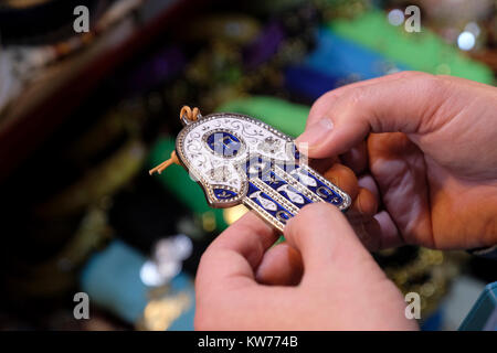 Ein Mann hält eine traditionelle Hand von Miriam oder Hamsa Amulett zur Abwehr des Bösen Auge in einem Souvenirshop in der Altstadt von Jerusalem. Israel Stockfoto